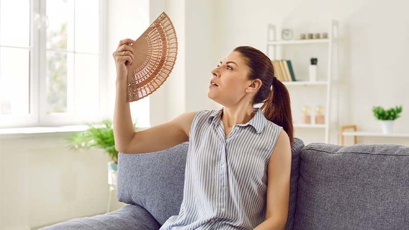 Mulher a abanar-se com um leque na sala durante uma vaga de calor